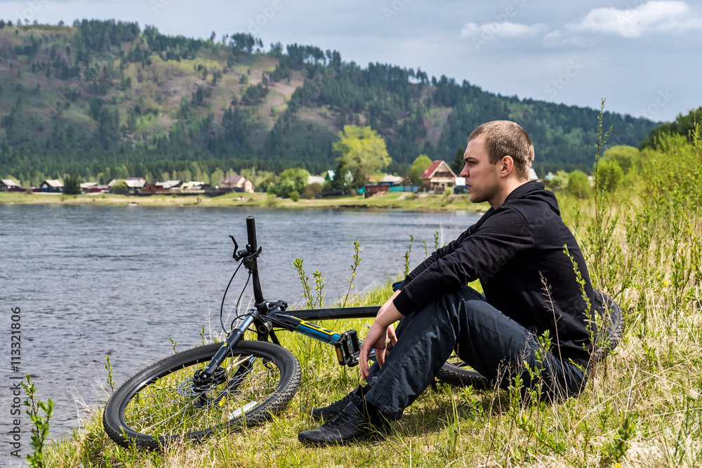 Obraz premium cyclist sits on the bank of river Irkut
