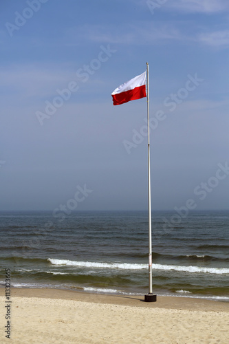 Fototapeta Naklejka Na Ścianę i Meble -  Polska flaga na maszcie nad brzegiem Bałtyku