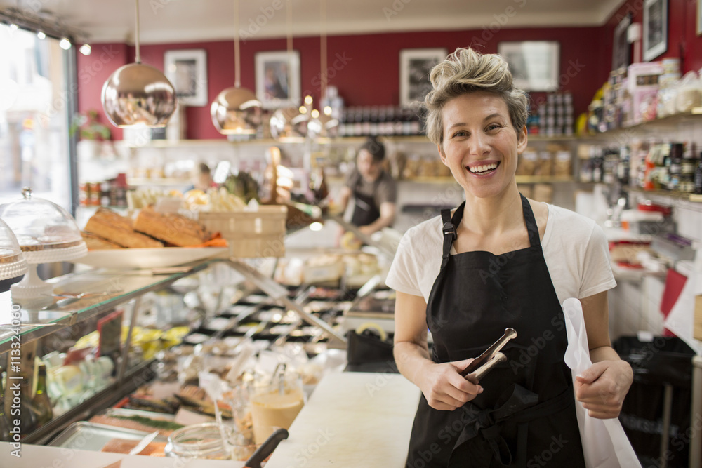 Portrait of happy saleswoman cutting cheese at counter in supermarket Portrait of happy saleswoman cutting cheese at counter in supermarket