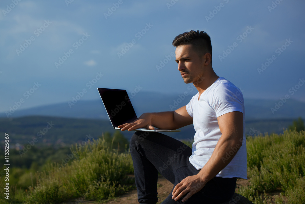 Pensive muscular man with laptop outdoor