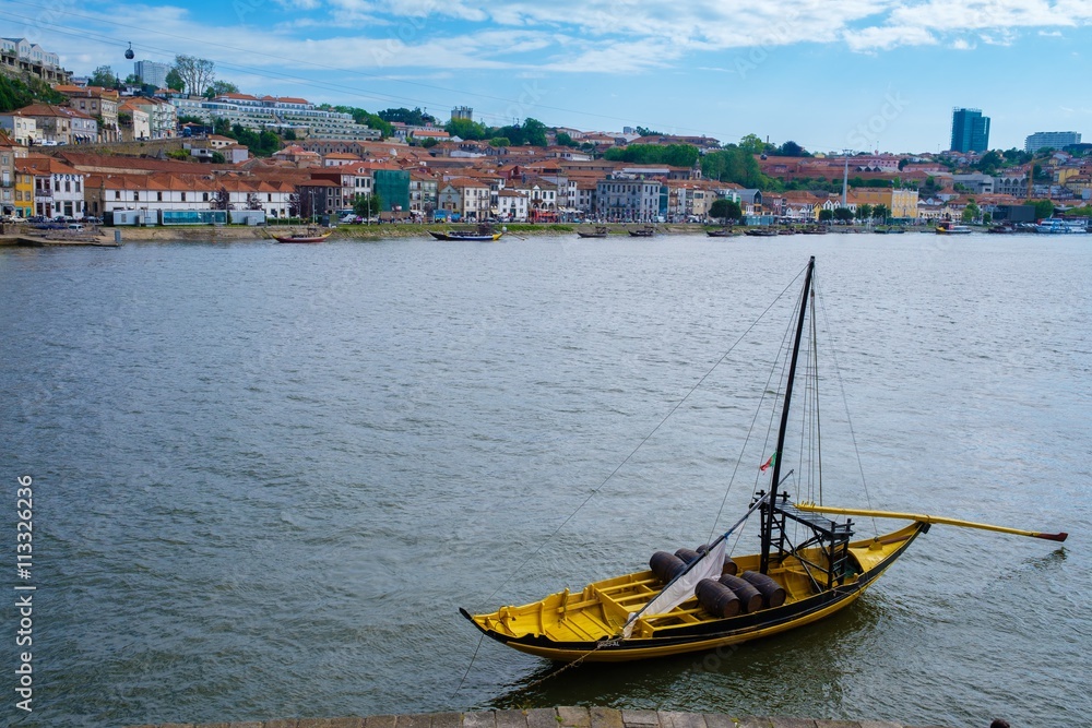 The iconic Rabelo boats, traditional Port wine transport on Douro river, with authentic Ribeira District view, Porto, Portugal.