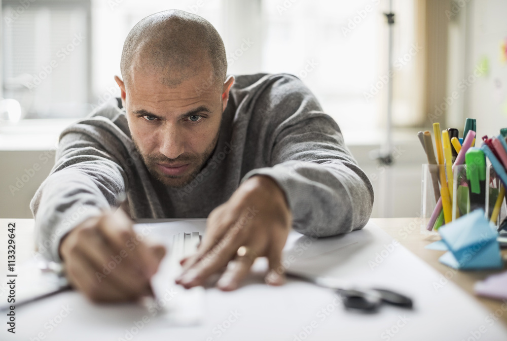 Businessman drawing line on paper at desk in creative office Businessman drawing line on paper at desk in creative office