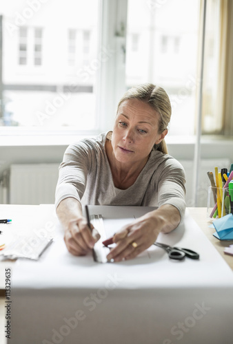 Mature businesswoman drawing line using ruler on paper photo