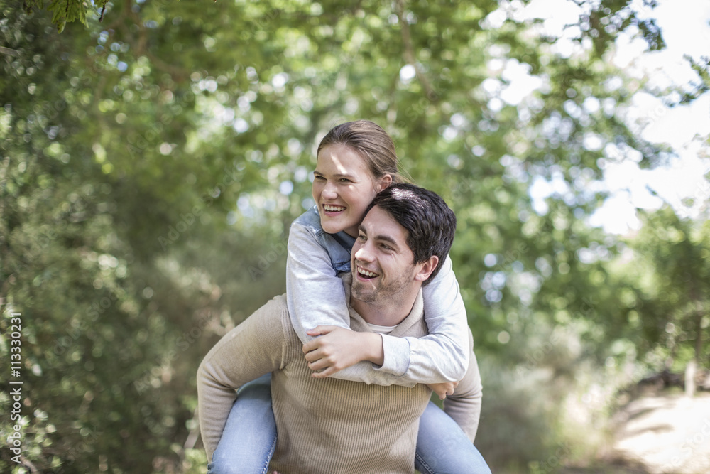Young man carrying his girfriend piggyback in the nature Young man carrying his girfriend piggyback in the nature