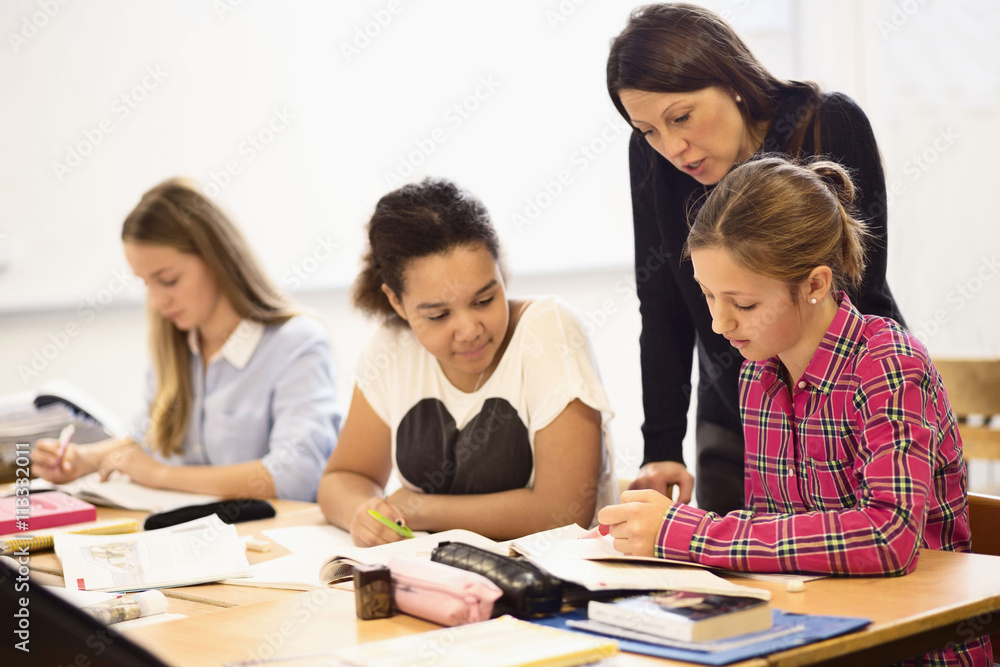 Mature female teacher teaching schoolgirls in classroom Mature female teacher teaching schoolgirls in classroom