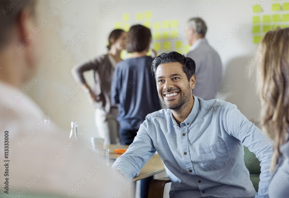 © Maskot - Happy businessman discussing with colleagues in board room