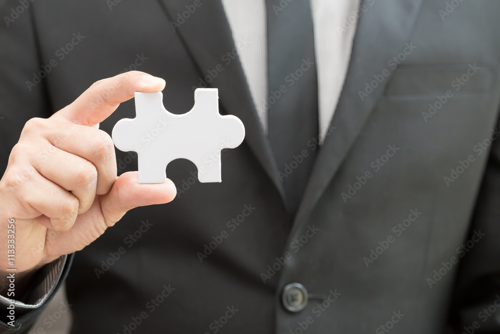 Businessman holding white jigsaw piece Businessman holding white jigsaw piece