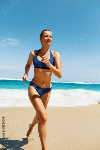 Beach Run. Fitness Woman Running On Sand. Beautiful Healthy Happy Smiling Girl With Sexy Fit Body In Sport Bikini Swimwear Having Fun On Summer Vacations Near Sea. Active Lifestyle, Recreation Concept