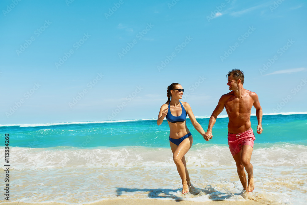 Couple Fun On Beach. Romantic People In Love Running On Sand At Luxury Sea Resort. Handsome Happy Man, Beautiful Smiling Woman Laughing Together On Summer Travel Vacation. Relationships, Summertime Couple Fun On Beach. Romantic People In Love Running On Sand At Luxury Sea Resort. Handsome Happy Man, Beautiful Smiling Woman Laughing Together On Summer Travel Vacation. Relationships, Summertime