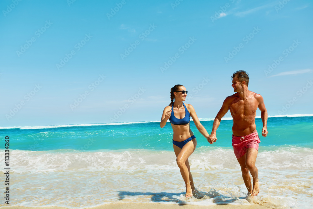 Couple Fun On Beach. Romantic People In Love Running On Sand At Luxury Sea Resort. Handsome Happy Man, Beautiful Smiling Woman Laughing Together On Summer Travel Vacation. Relationships, Summertime