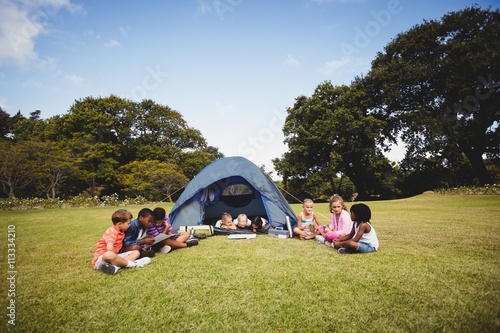  Smiling kids lying and reading in the tent together