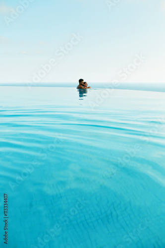 Couple In Love At Luxury Resort On Romantic Summer Vacation. People Relaxing Together In Edge Swimming Pool Water, Enjoying Beautiful Sea View. Happy Lovers On Honeymoon Travel. Relationship, Romance © puhhha