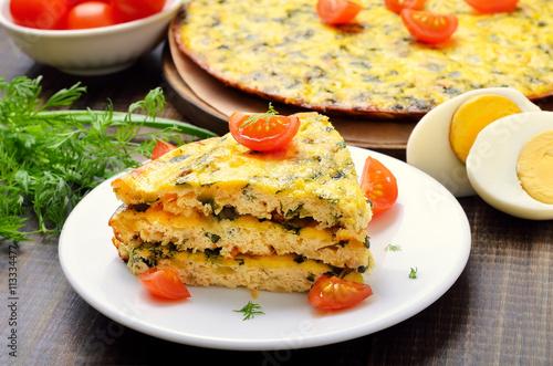 Homemade omelet with herbs and vegetables on wooden background,