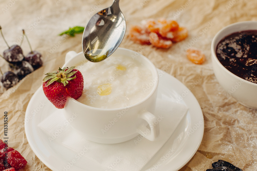 Rice porrige with strawberry and oil spoon on parchment background Rice porrige with strawberry and oil spoon on parchment background