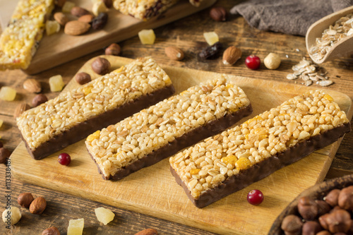Granola bars. Healthy food: energy granola bars with cornflakes, puffed cereals and rolled oats covered in chocolate on wooden cutting board