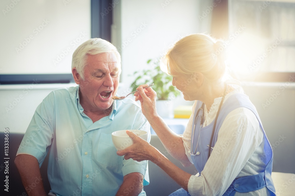 Obraz premium Female doctor feeding senior man