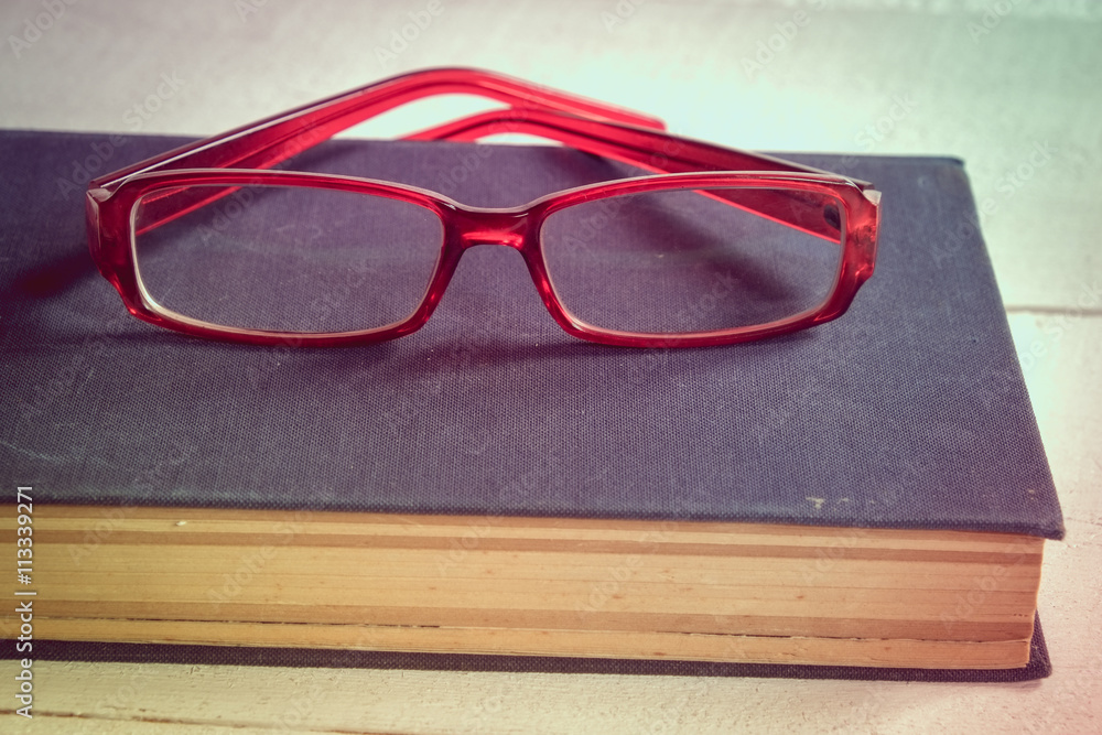 Old books and glasses on a wooden table with filter effect retro vintage style Old books and glasses on a wooden table with filter effect retro vintage style