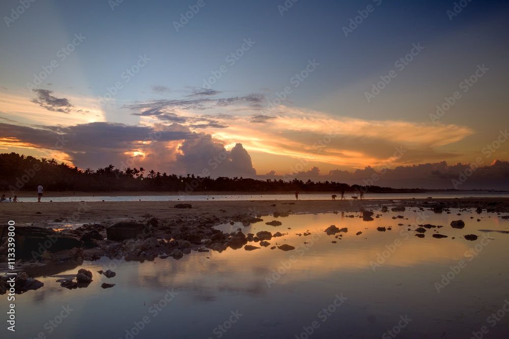 Sunset scene with mirror reflection on a tropical sea beach. in Bali.