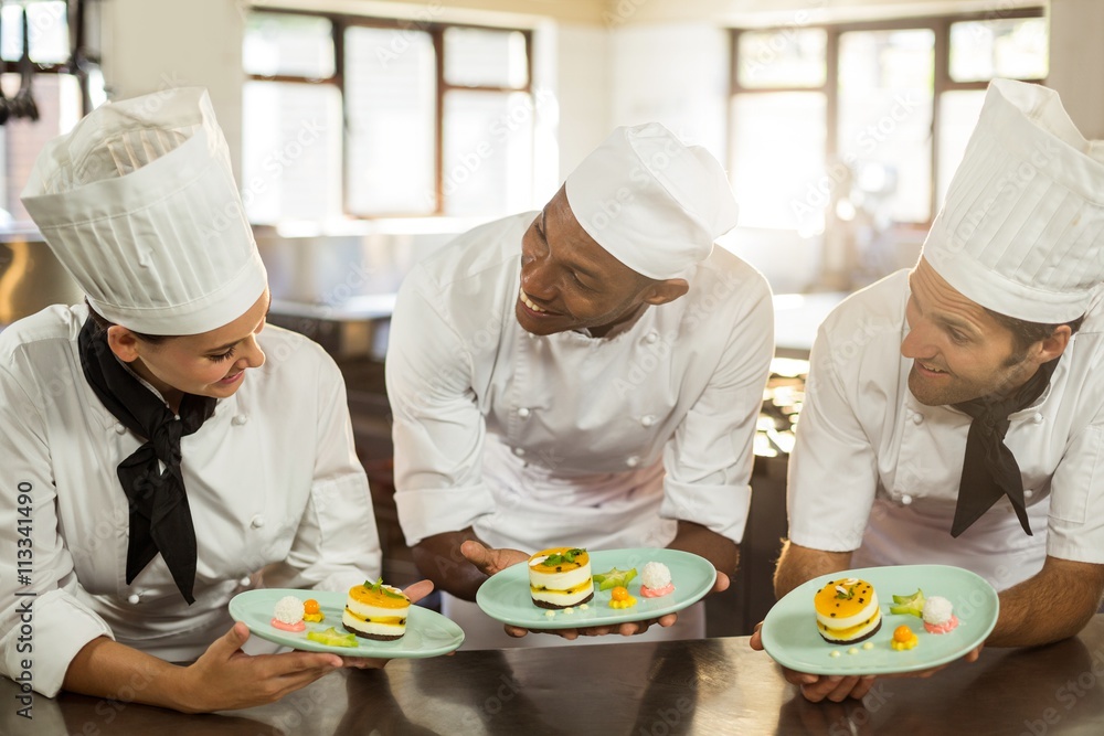 Smiling chefs team holding dessert plates Smiling chefs team holding dessert plates