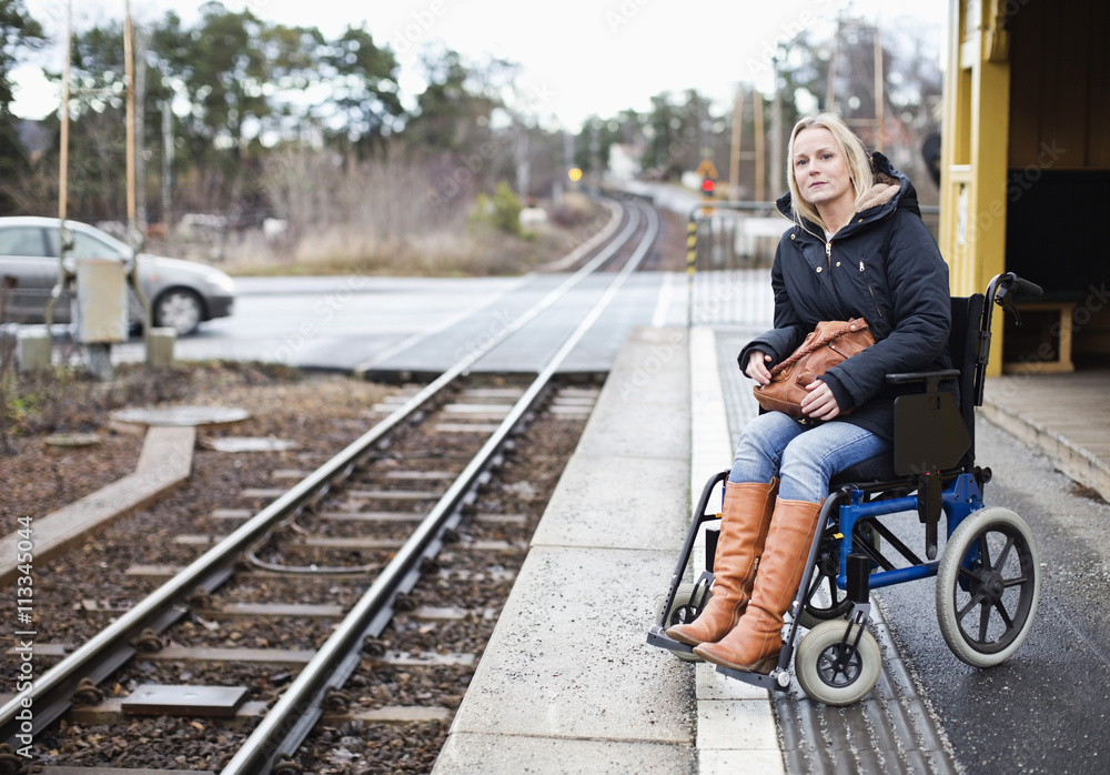 Disabled woman in wheelchair waiting for the train at railway station
