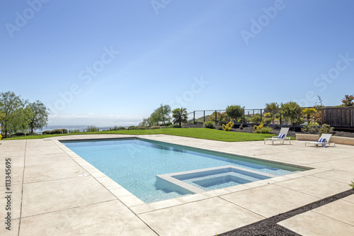 Luxury swimming pool and blue water with lounging chairs.  © coralimages