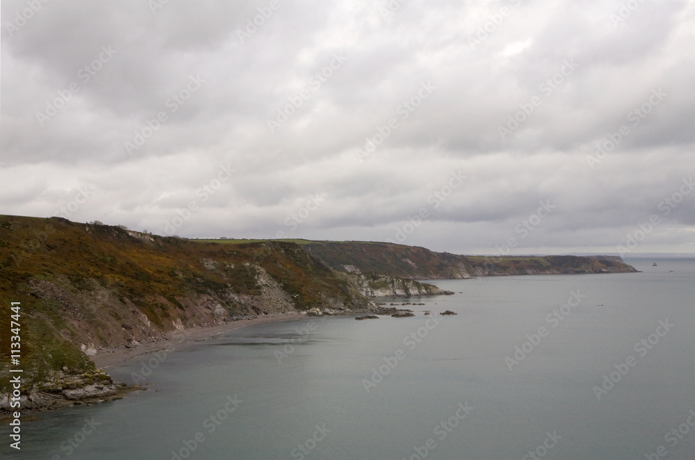 Coastline between Brixham and Dartmouth, Devon. The coastline between Brixham and Dartmouth is rocky and dramatic. A coastal walk follows the coast between the two towns.