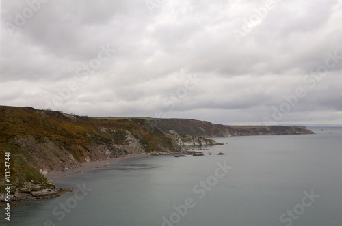 Coastline between Brixham and Dartmouth, Devon. The coastline between Brixham and Dartmouth is rocky and dramatic. A coastal walk follows the coast between the two towns.