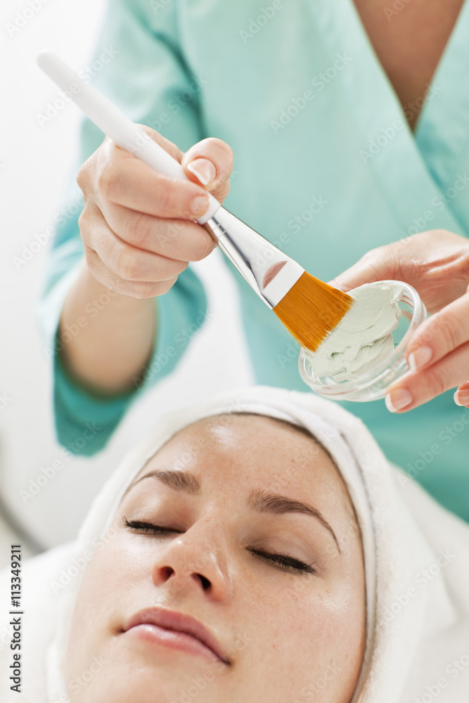 Midsection of a beautician applying cream with make-up brush to young woman Midsection of a beautician applying cream with make-up brush to young woman