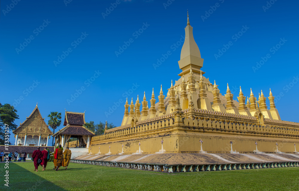 Naklejka premium Group of Buddhist monks walking around That Luang Stupa, landmark of Vientiane, Lao PDR