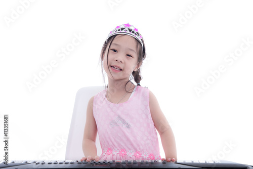 Asian girl in princess dress playing keyboard on white. photo