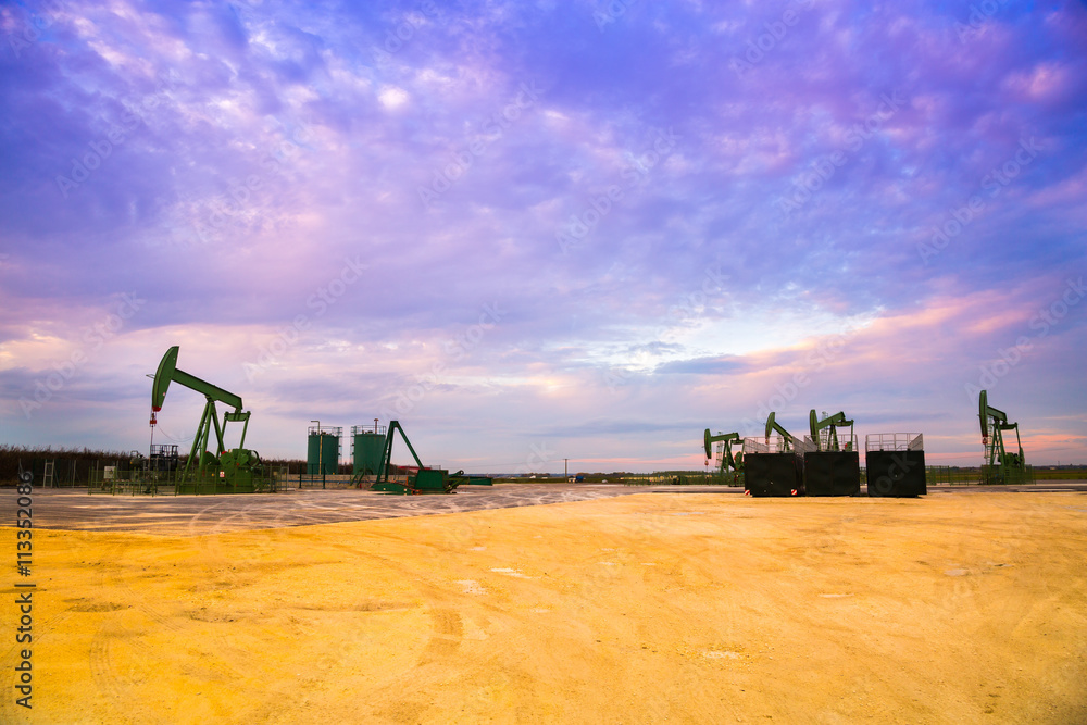 Fototapeta premium Silhouette of Oil pumps at oil field with sunset sky background
