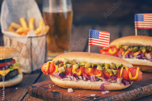 American hot dog with pickles,onions, ketchup, mustard and french fries at a Picnic for 4th of July 
