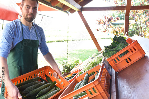 regionaler Gemüseanbau: Bauer mit Stiegen Gurken zum Verkauf auf dem Bauernhof