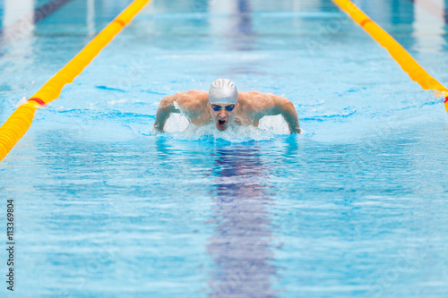 dynamic and fit swimmer in cap breathing performing the butterfly stroke © satyrenko