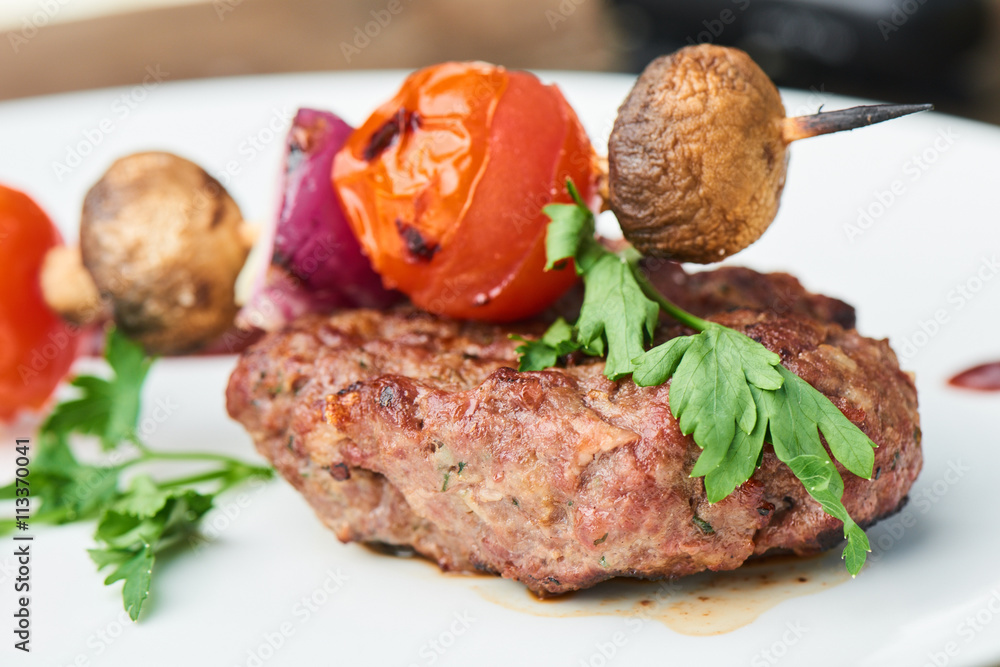 Steak and vegetables on skewers, served on a white plate Steak and vegetables on skewers, served on a white plate