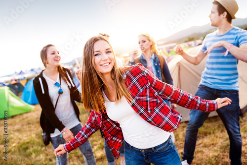 Group of teenagers at summer music festival dancing