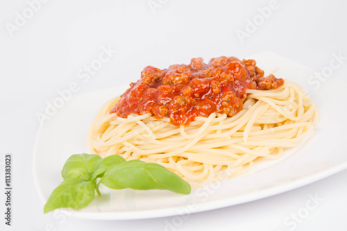 Spaghetti bolognese decorated with basil on a white background