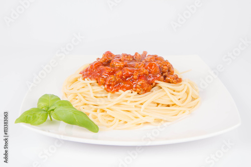 Spaghetti bolognese decorated with basil on a white background