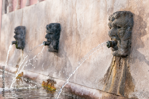 Fountain with lava stone mascarons in one small village at the bottom of Mount Etna, Sicily