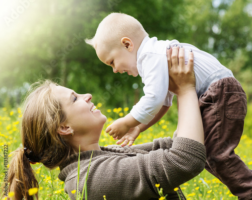 Happy family, mother lifts her son on nature background