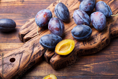 Fresh organic plums on rustic wooden cutting board