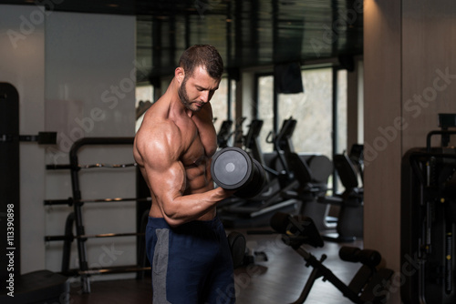 Man In The Gym Exercising Biceps With Dumbbells