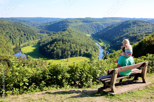 Father and child hiking and enjoying view from famous panoramic point of The Giant's tomb of the river Semois, located nearby the city of Bouillon, Wallonia, Ardennes, Belgium.