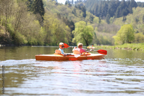 Two boys kayaking on the river. Active happy friends, teenage schoolboys, having fun together enjoying adventurous experience with kayak on a sunny day during summer vacation