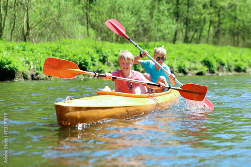 Two boys kayaking on the river. Active happy friends, teenage schoolboys, having fun together enjoying adventurous experience with kayak on a sunny day during summer vacation