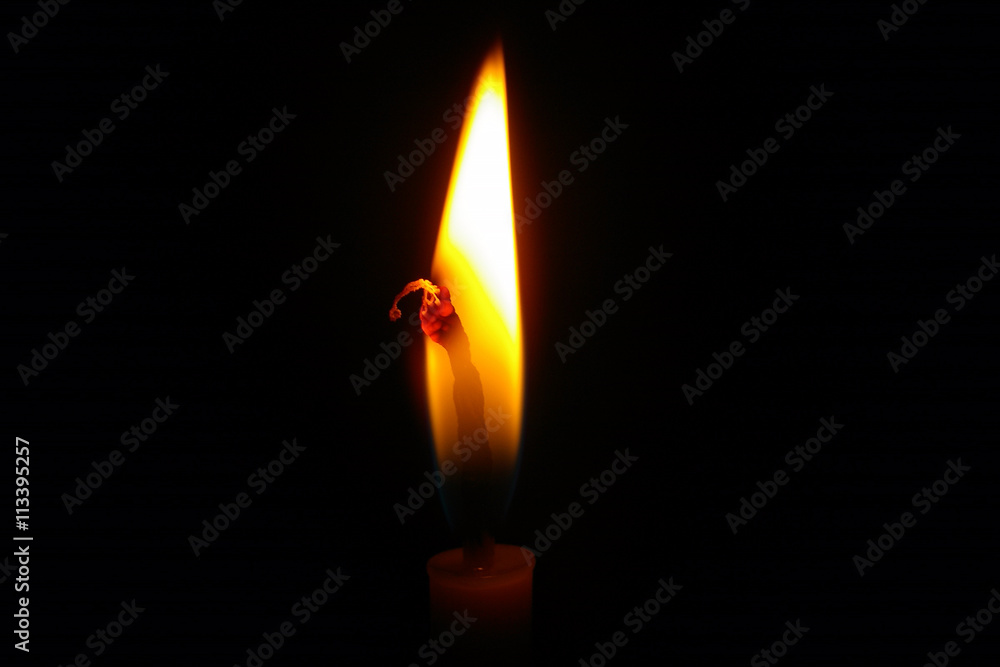 Candle light/One light candle burning brightly in the black background.Candle flame closeup isolated on black.