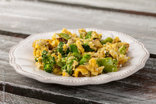 Scrambled eggs with broccoli, onions, and green bell peppers side view