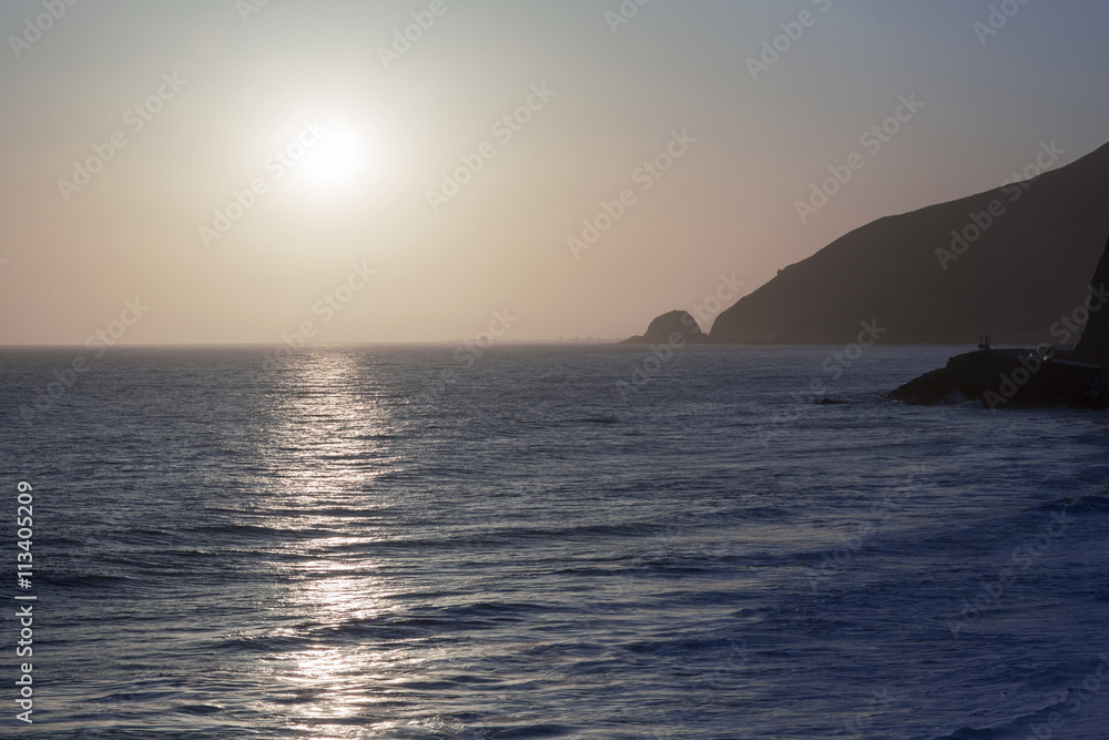 The Pacific ocean during sunset. Landscape with blue sea, the mountains and the dusk sky, the USA, California. 