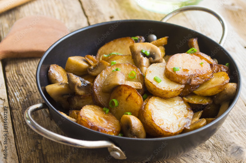 Fried potatoes with mushrooms in a frying pan
