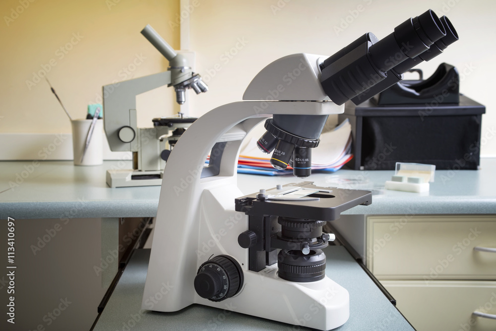 Professional microscope close-up with chemist scientific researcher hands using microscope in the laboratory interior. Professional microscope close-up with chemist scientific researcher hands using microscope in the laboratory interior.